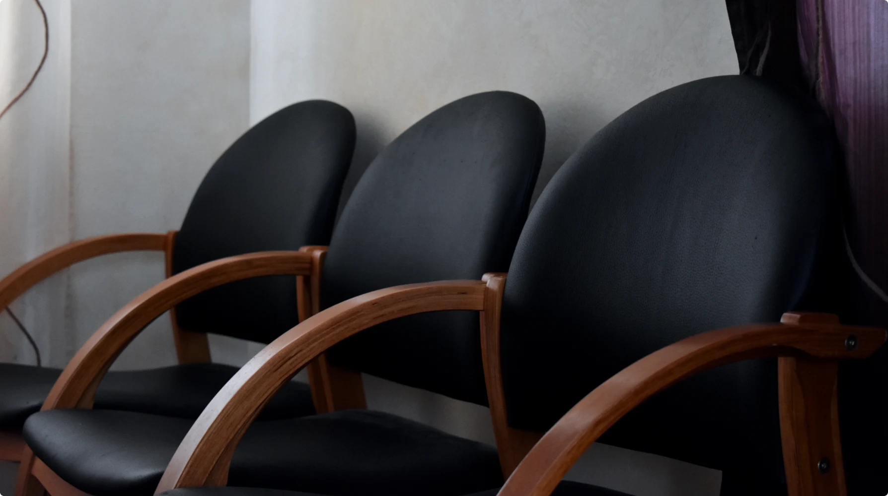 Three black chairs with curved wooden armrests in a contemporary interior